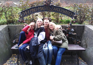 Uczestnicy wycieczki na ławce z napisem Chełmno - miasto zakochanych