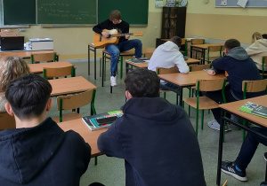 uczeń gra na gitarze, reszta klasy słucha